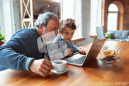 Image of Grandfather and his grandson spending time insulated at home, stadying, watching cinema, shopping together