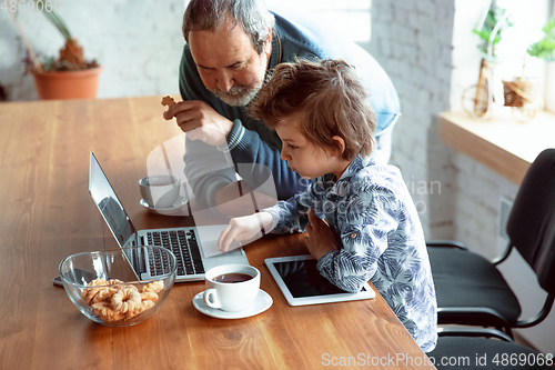 Image of Grandfather and his grandson spending time insulated at home, stadying, watching cinema, shopping together