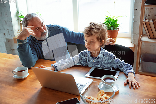 Image of Grandfather and his grandson spending time insulated at home, stadying, watching cinema, shopping together