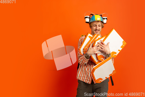 Image of Contacless delivery service during quarantine. Man delivers food and shopping bags during insulation. Emotions of deliveryman isolated on orange background.