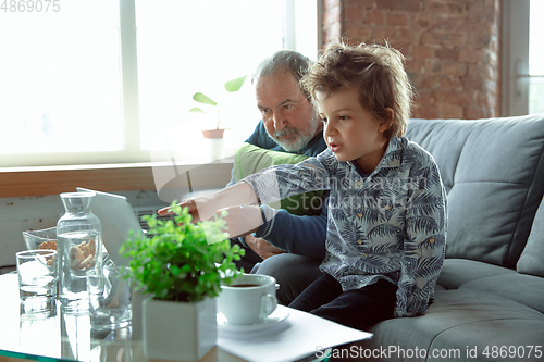 Image of Grandfather and his grandson spending time insulated at home, stadying, watching cinema, shopping together