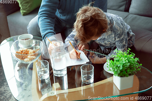 Image of Grandfather and his grandson spending time insulated at home, stadying, writing, drawing or playing together