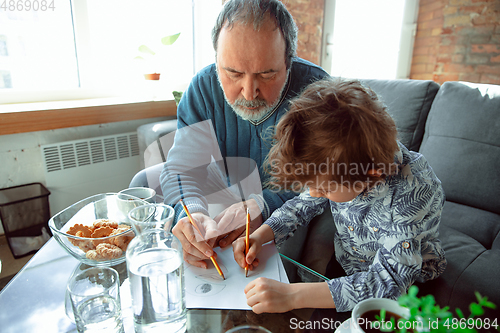 Image of Grandfather and his grandson spending time insulated at home, stadying, writing, drawing or playing together