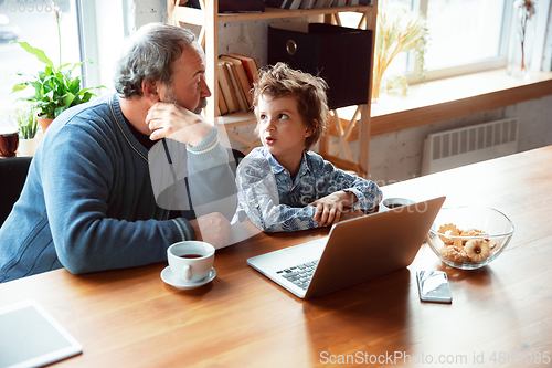 Image of Grandfather and his grandson spending time insulated at home, stadying, watching cinema, shopping together