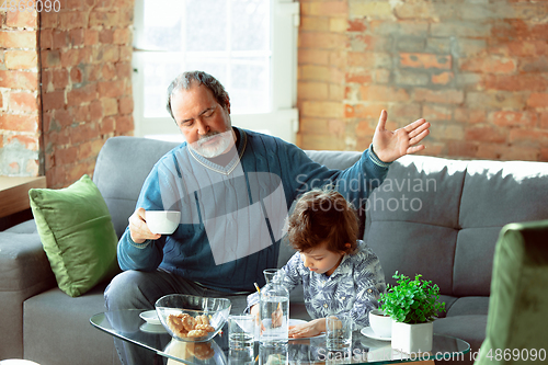 Image of Grandfather and his grandson spending time insulated at home, stadying, writing, drawing or playing together