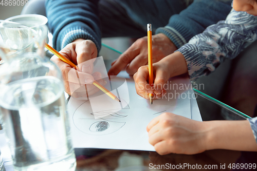 Image of Grandfather and his grandson spending time insulated at home, stadying, writing, drawing or playing together, close up of hands