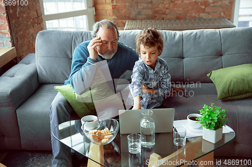 Image of Grandfather and his grandson spending time insulated at home, stadying, watching cinema, shopping together