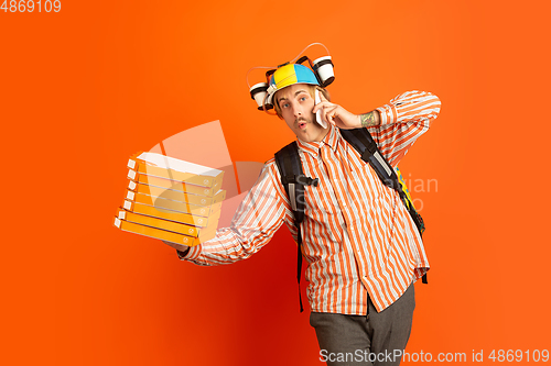 Image of Contacless delivery service during quarantine. Man delivers food and shopping bags during insulation. Emotions of deliveryman isolated on orange background.