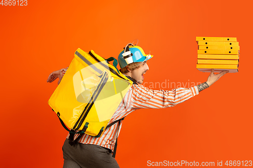 Image of Contacless delivery service during quarantine. Man delivers food and shopping bags during insulation. Emotions of deliveryman isolated on orange background.