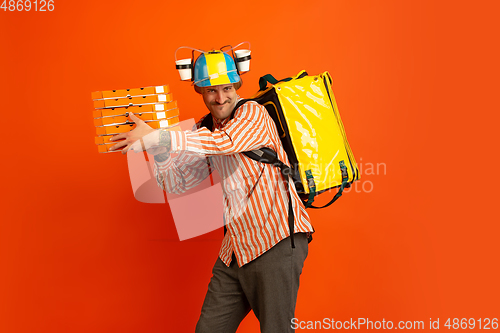 Image of Contacless delivery service during quarantine. Man delivers food and shopping bags during insulation. Emotions of deliveryman isolated on orange background.