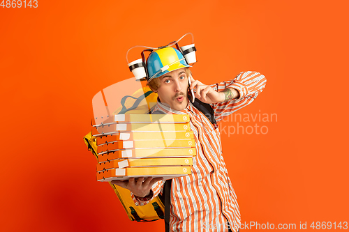 Image of Contacless delivery service during quarantine. Man delivers food and shopping bags during insulation. Emotions of deliveryman isolated on orange background.