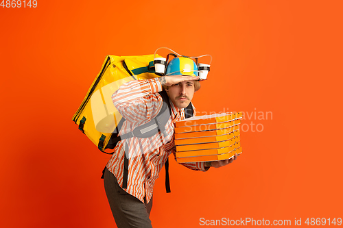 Image of Contacless delivery service during quarantine. Man delivers food and shopping bags during insulation. Emotions of deliveryman isolated on orange background.