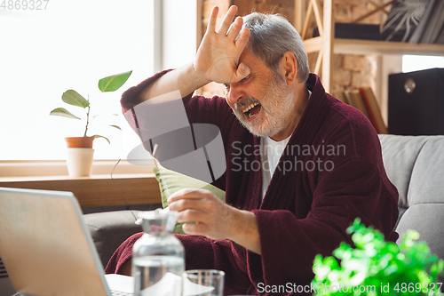 Image of Mature senior older man during quarantine, realizing how important stay at home during virus outbreak, suffers of glaucoma, eye deseases