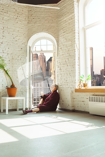 Image of Mature senior older man during quarantine, realizing how important stay at home during virus outbreak, looking throught window on day New York city