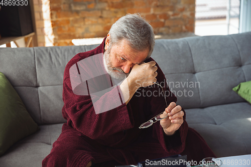 Image of Mature senior older man during quarantine, realizing how important stay at home during virus outbreak, suffers of glaucoma, eye deseases