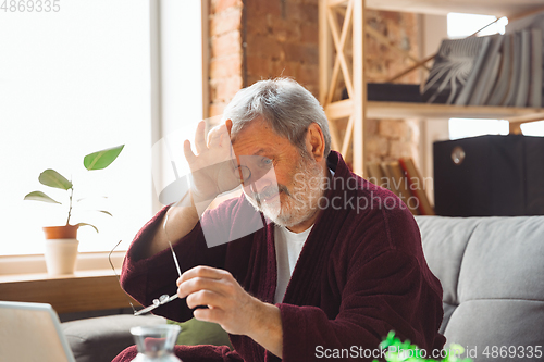 Image of Mature senior older man during quarantine, realizing how important stay at home during virus outbreak, suffers of glaucoma, eye deseases