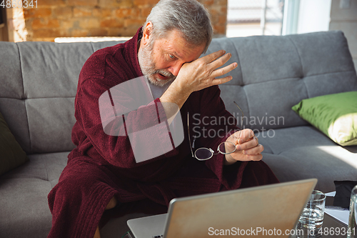 Image of Mature senior older man during quarantine, realizing how important stay at home during virus outbreak, suffers of glaucoma, eye deseases