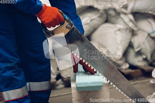 Image of Close up of hands of repairman, professional builder working outdoors, repairing