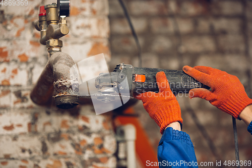 Image of Close up of hands of repairman, professional builder working outdoors, repairing