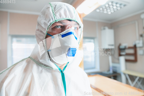 Image of Coronavirus Pandemic. A disinfector in a protective suit and mask sprays disinfectants in the house or office