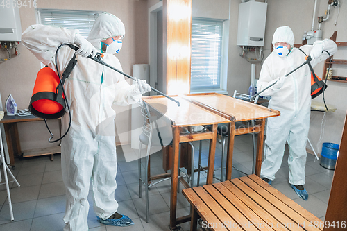 Image of Coronavirus Pandemic. A disinfector in a protective suit and mask sprays disinfectants in the house or office