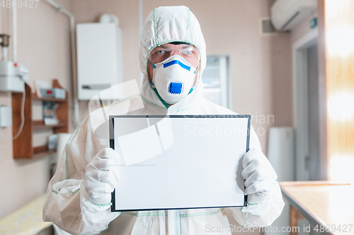 Image of Coronavirus Pandemic. A disinfector in a protective suit and mask sprays disinfectants in the house or office