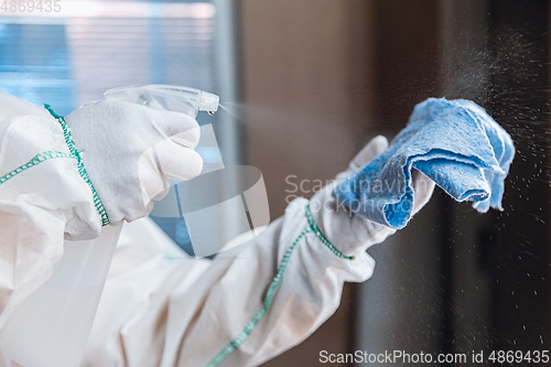 Image of Coronavirus Pandemic. A disinfector in a protective suit and mask sprays disinfectants in the house or office