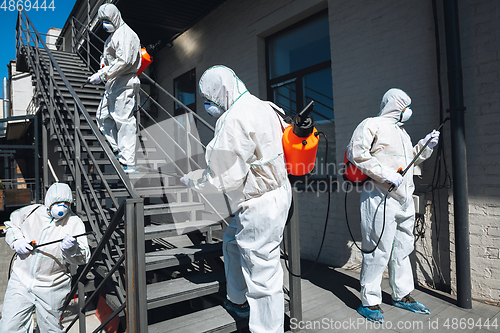 Image of Coronavirus Pandemic. A disinfectors in a protective suit and mask spray disinfectants in the house or office