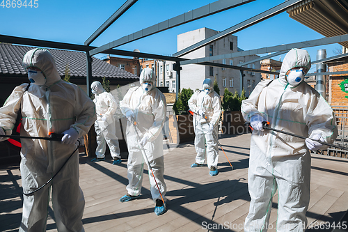 Image of Coronavirus Pandemic. A disinfectors in a protective suit and mask spray disinfectants in the house or office