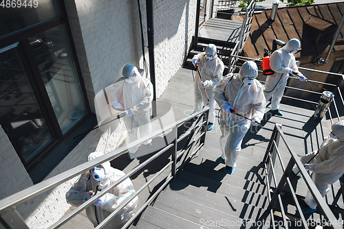 Image of Coronavirus Pandemic. A disinfectors in a protective suit and mask spray disinfectants in the house or office