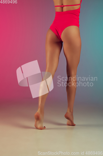Image of Close up fashion portrait of young fit and sportive woman in stylish pink luxury swimwear on gradient background. Perfect body ready for summertime.