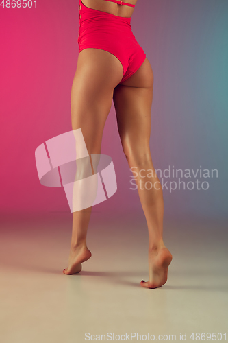 Image of Close up fashion portrait of young fit and sportive woman in stylish pink luxury swimwear on gradient background. Perfect body ready for summertime.