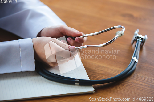 Image of Close up of doctors hands with stethoscope, sheets and pills on wooden background