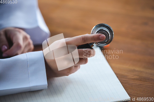 Image of Close up of doctors hands with stethoscope, sheets and pills on wooden background