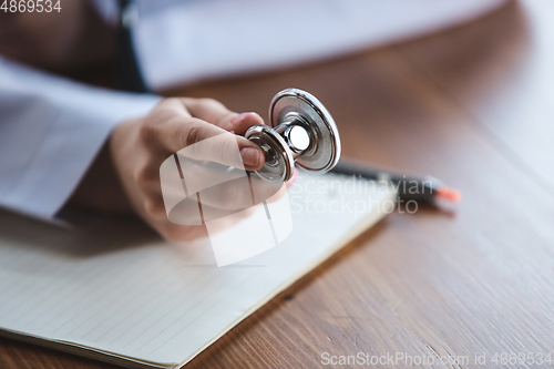 Image of Close up of doctors hands with stethoscope, sheets and pills on wooden background