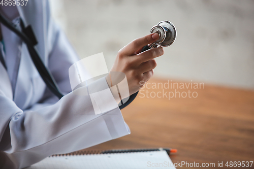 Image of Close up of doctors hands with stethoscope, sheets and pills on wooden background