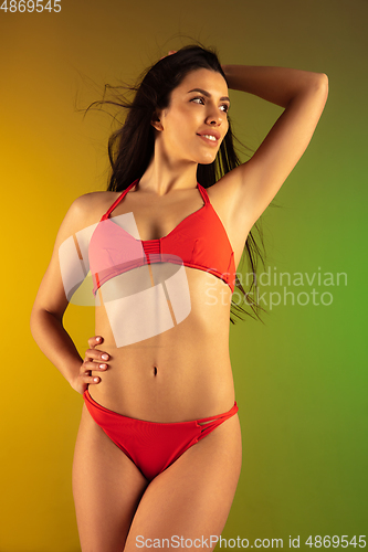 Image of Close up fashion portrait of young fit and sportive woman in stylish red luxury swimwear on gradient background. Perfect body ready for summertime.