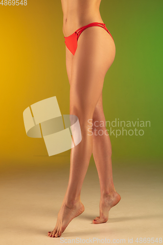 Image of Close up fashion portrait of young fit and sportive woman in stylish red luxury swimwear on gradient background. Perfect body ready for summertime.