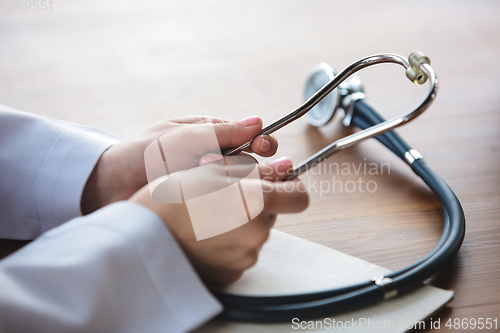 Image of Close up of doctors hands with stethoscope, sheets and pills on wooden background