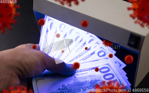 Image of Male hands checking of banknotes in the detector, 3D models of coronavirus spreding around