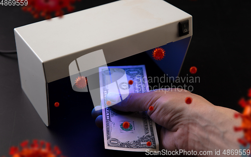 Image of Male hands checking of banknotes in the detector, 3D models of coronavirus spreding around