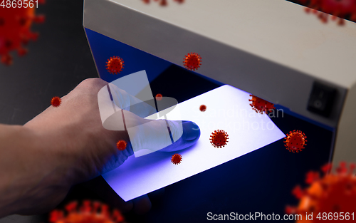 Image of Male hands checking of banknotes in the detector, 3D models of coronavirus spreding around
