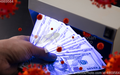 Image of Male hands checking of banknotes in the detector, 3D models of coronavirus spreding around