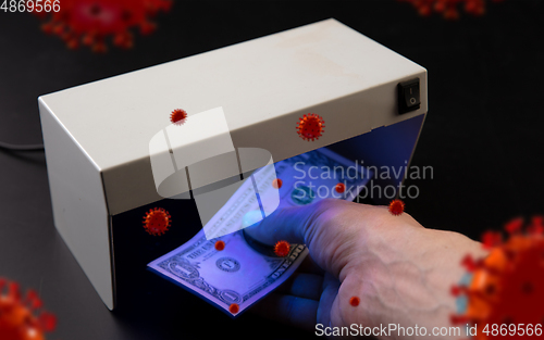 Image of Male hands checking of banknotes in the detector, 3D models of coronavirus spreding around