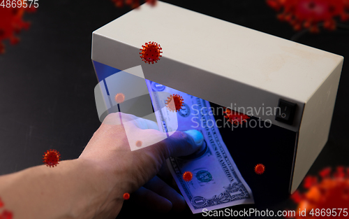 Image of Male hands checking of banknotes in the detector, 3D models of coronavirus spreding around