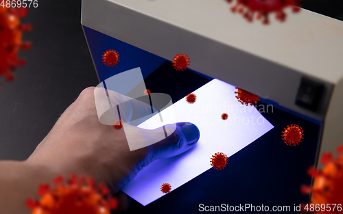 Image of Male hands checking of banknotes in the detector, 3D models of coronavirus spreding around