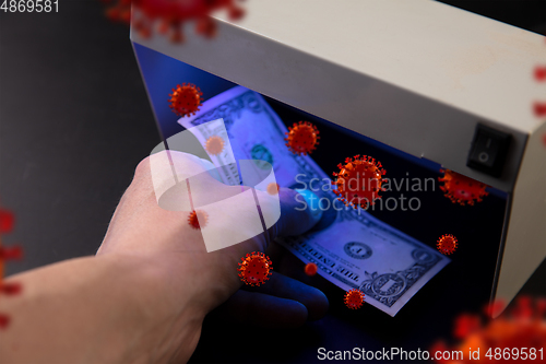 Image of Male hands checking of banknotes in the detector, 3D models of coronavirus spreding around