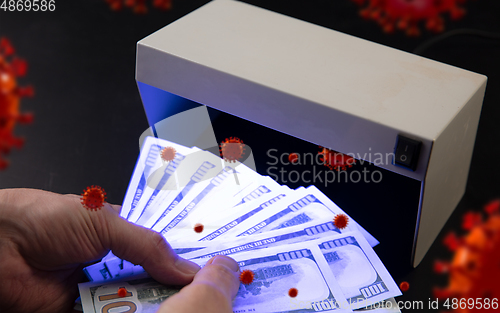 Image of Male hands checking of banknotes in the detector, 3D models of coronavirus spreding around