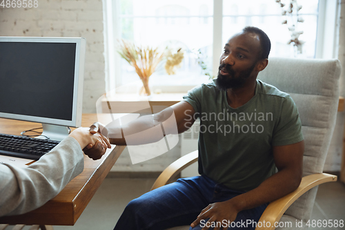 Image of Young man sitting in office during the job interview with female employee, boss or HR-manager, talking, thinking, looks confident