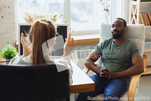 Image of Young man sitting in office during the job interview with female employee, boss or HR-manager, talking, thinking, looks confident